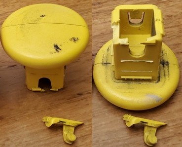 Broken yellow plastic cap from F-250 tailgate step handle, showing the cracked locking mechanism