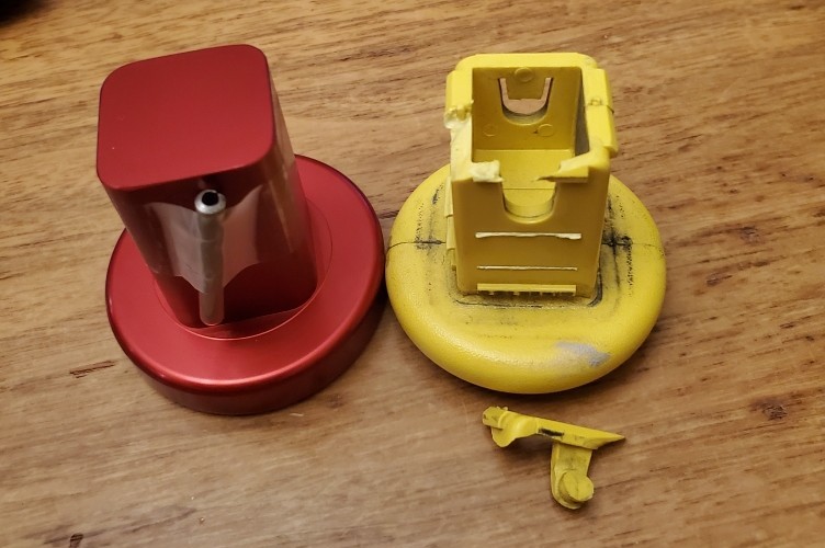 Side-by-side comparison: the broken yellow OEM cap next to the new ruby red machined aluminum replacement, with locking pin